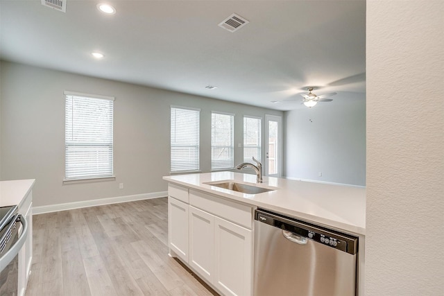 kitchen featuring stainless steel dishwasher, light wood-style floors, light countertops, and a sink