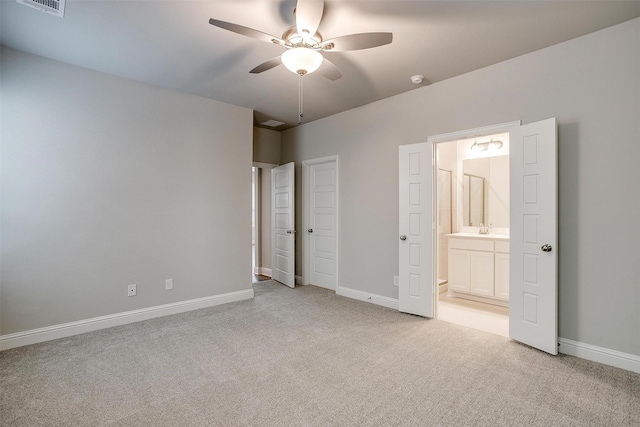 unfurnished bedroom featuring light colored carpet, a sink, baseboards, and ensuite bathroom