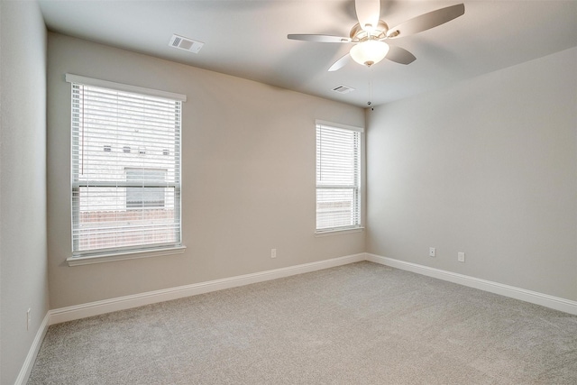 carpeted empty room featuring baseboards, visible vents, and a ceiling fan