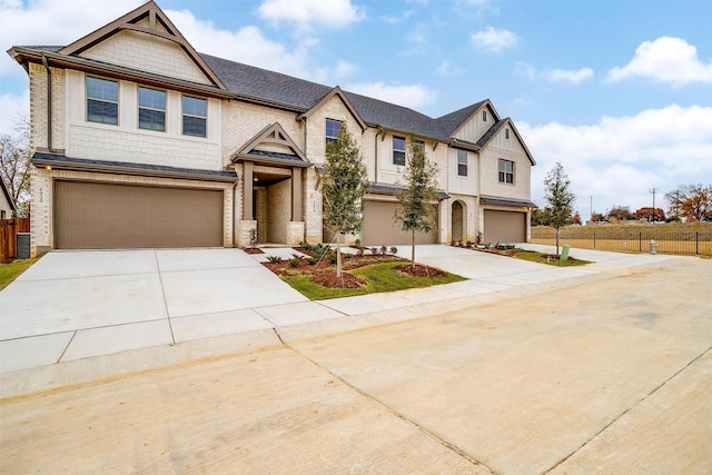 view of front facade featuring driveway, a garage, and fence