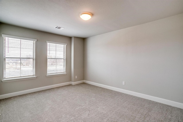 unfurnished room featuring visible vents, light carpet, and baseboards