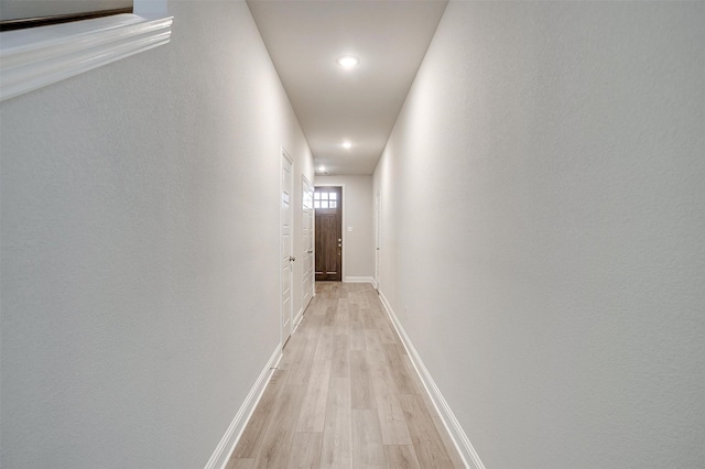 hallway with light wood-type flooring and baseboards