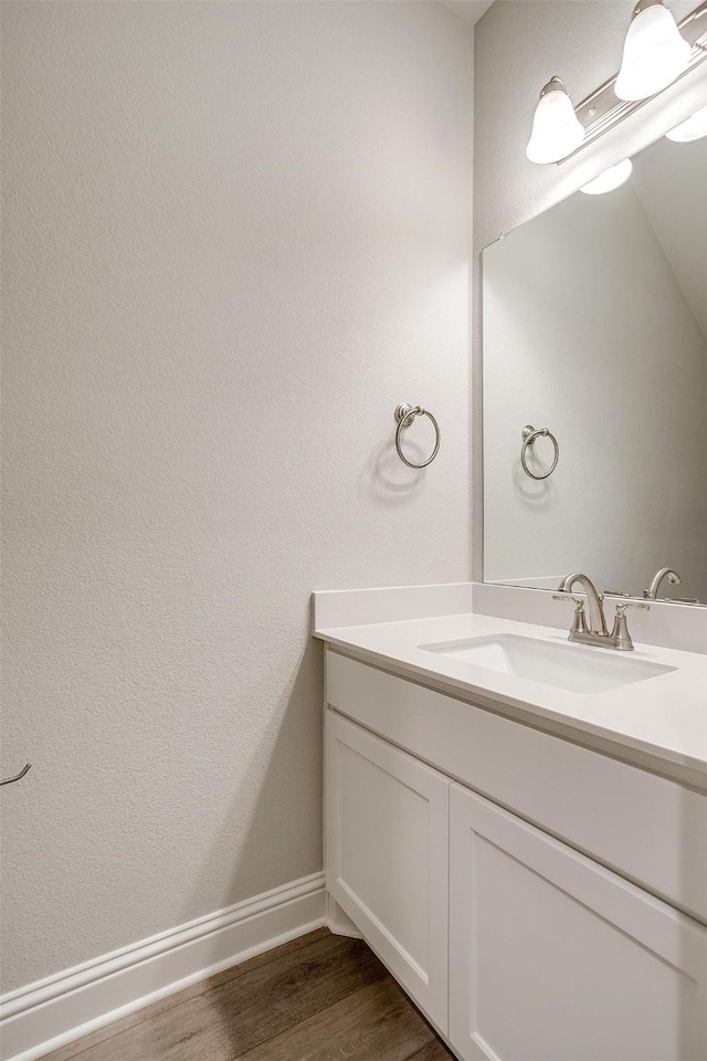 bathroom with wood finished floors, vanity, and baseboards