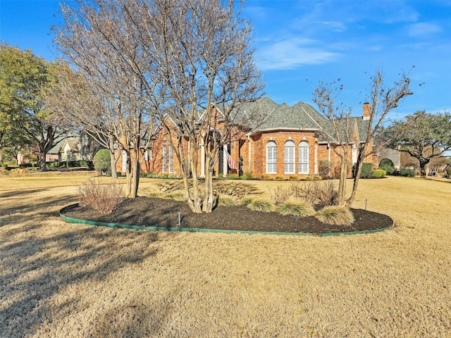 view of front facade with brick siding and a front lawn