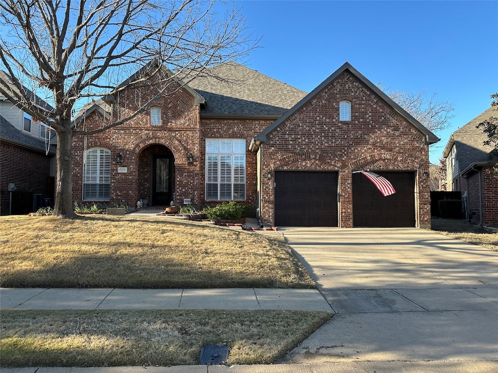 traditional-style house featuring a garage, concrete driveway, brick siding, and roof with shingles