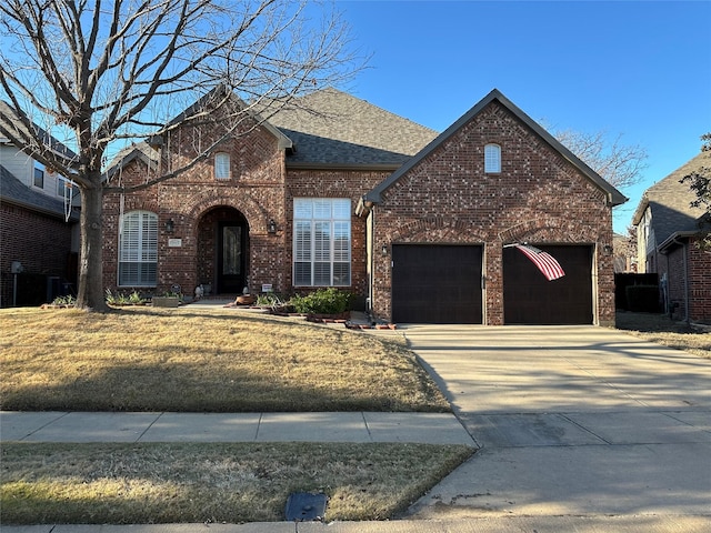 traditional-style home with brick siding, concrete driveway, an attached garage, and a shingled roof