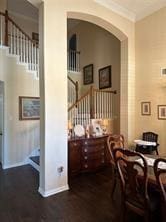 dining space featuring wood finished floors, baseboards, arched walkways, ornamental molding, and stairs