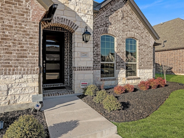 view of exterior entry featuring brick siding and stone siding