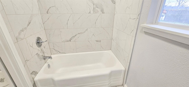 bathroom featuring bathtub / shower combination and a textured wall