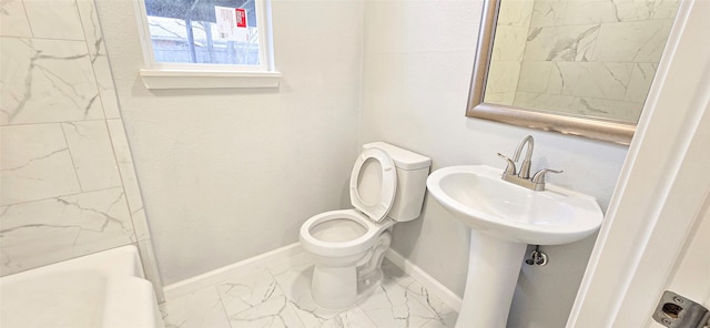 bathroom with toilet, a sink, baseboards, marble finish floor, and a bath