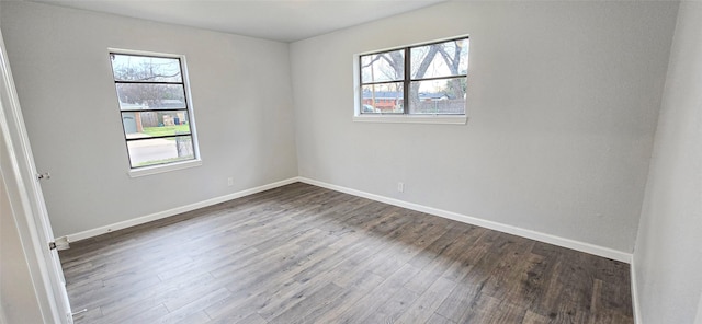 spare room with baseboards and wood finished floors