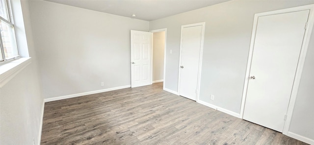 unfurnished bedroom with wood finished floors and baseboards