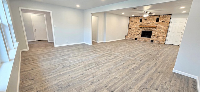 unfurnished living room featuring a brick fireplace, recessed lighting, a ceiling fan, and wood finished floors