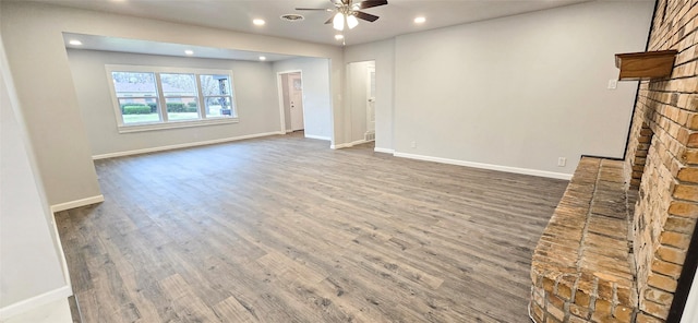 unfurnished living room with ceiling fan, recessed lighting, wood finished floors, baseboards, and a brick fireplace