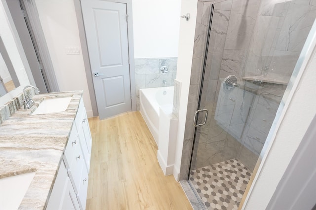 bathroom featuring a garden tub, a stall shower, wood finished floors, and vanity