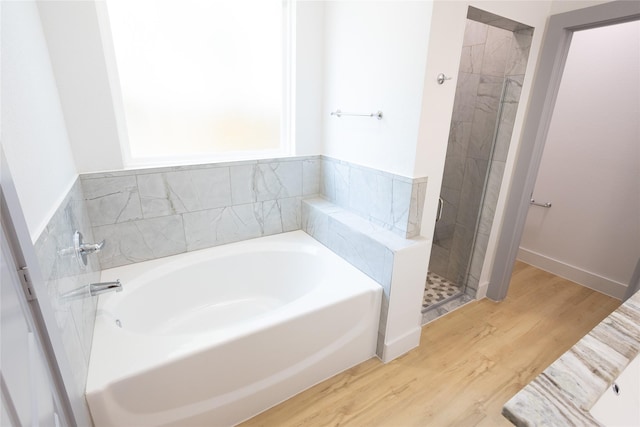 full bath featuring a garden tub, a shower stall, and wood finished floors