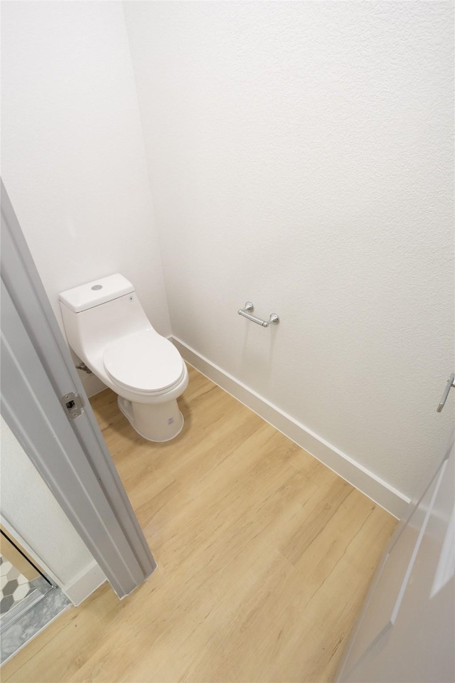 bathroom with baseboards, toilet, and wood finished floors