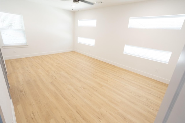 unfurnished room with ceiling fan, light wood finished floors, and baseboards