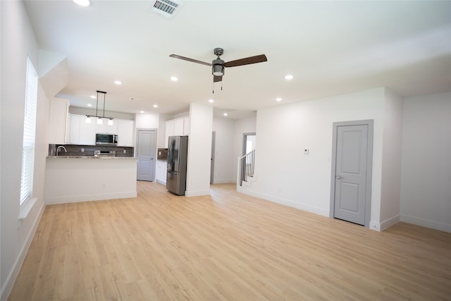 kitchen with light wood-style flooring, stainless steel appliances, backsplash, and open floor plan