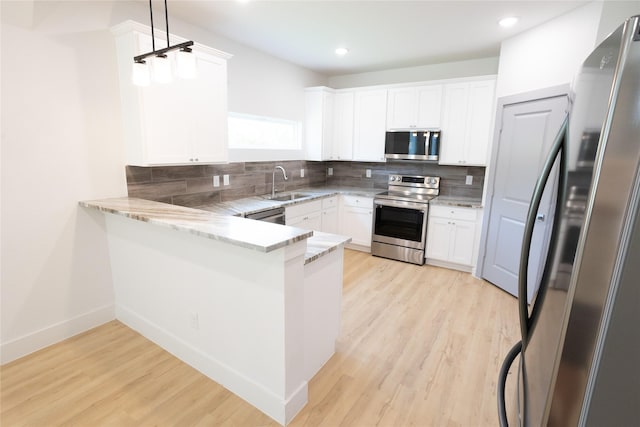 kitchen with tasteful backsplash, appliances with stainless steel finishes, a sink, light wood-type flooring, and a peninsula