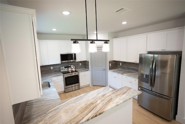 kitchen with light wood-style flooring, stainless steel appliances, visible vents, white cabinetry, and tasteful backsplash