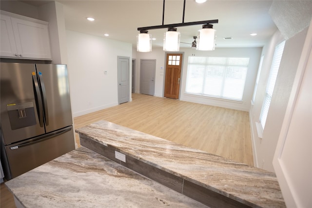 kitchen with light stone counters, light wood-style flooring, recessed lighting, baseboards, and stainless steel fridge with ice dispenser