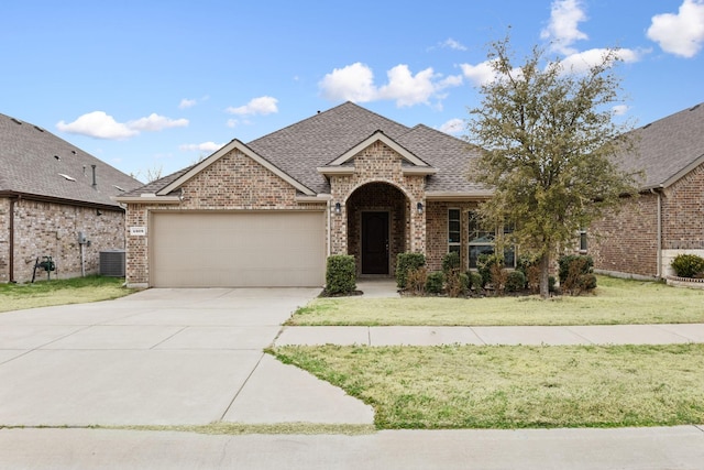 view of front of property with brick siding, roof with shingles, an attached garage, driveway, and a front lawn