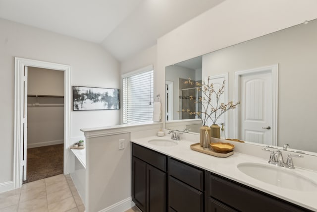 bathroom featuring a stall shower, vaulted ceiling, tile patterned flooring, and a sink