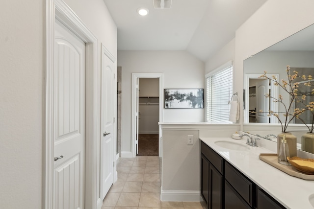 full bathroom with double vanity, tile patterned flooring, vaulted ceiling, and a sink