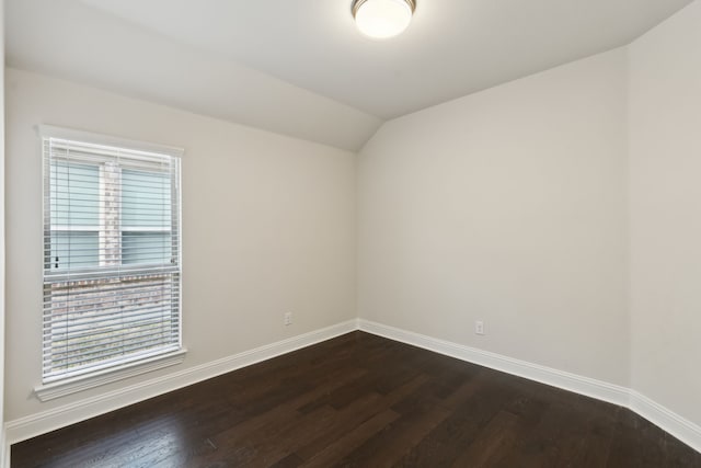 empty room with lofted ceiling, baseboards, and dark wood finished floors