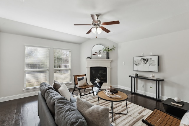 living area with lofted ceiling, wood finished floors, a glass covered fireplace, and baseboards