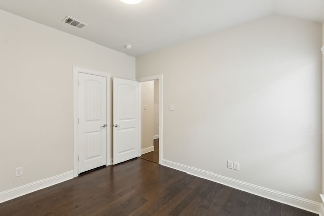 unfurnished bedroom featuring vaulted ceiling, visible vents, dark wood finished floors, and baseboards