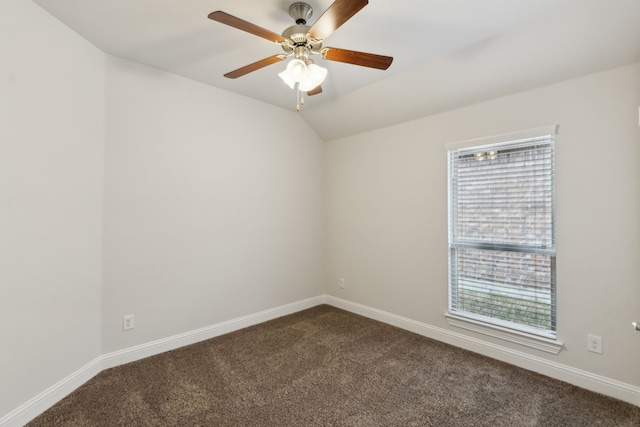 spare room featuring lofted ceiling, baseboards, a healthy amount of sunlight, and dark colored carpet