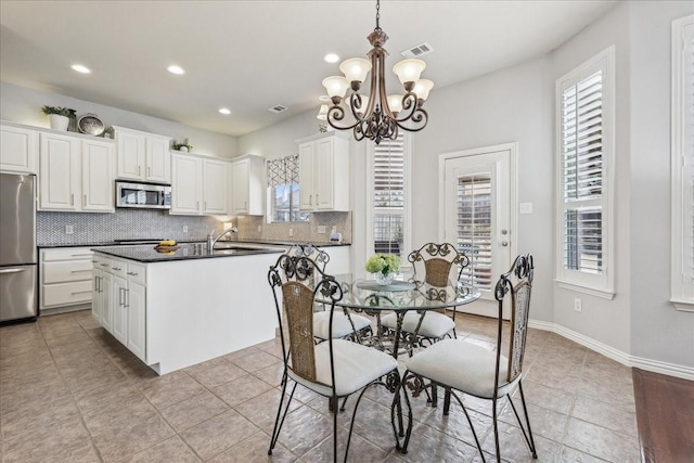 kitchen featuring a kitchen island with sink, stainless steel appliances, decorative backsplash, dark countertops, and plenty of natural light