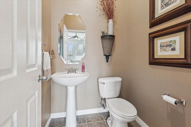 half bath featuring tile patterned flooring, toilet, and baseboards