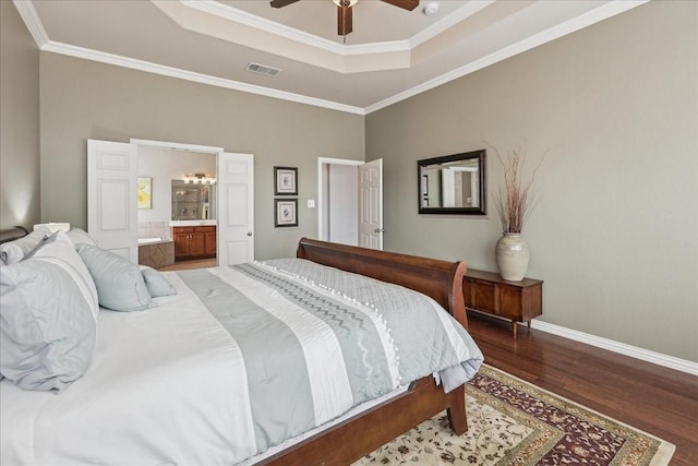 bedroom featuring wood finished floors, visible vents, baseboards, a tray ceiling, and crown molding