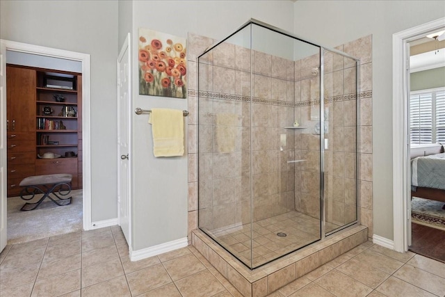 ensuite bathroom featuring ensuite bathroom, a stall shower, tile patterned flooring, and baseboards