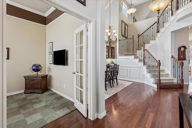 foyer featuring baseboards, a notable chandelier, stairway, and wood finished floors