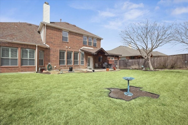 rear view of property with a yard, brick siding, a chimney, and fence