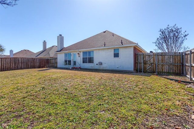 back of property with a gate, a lawn, and a fenced backyard