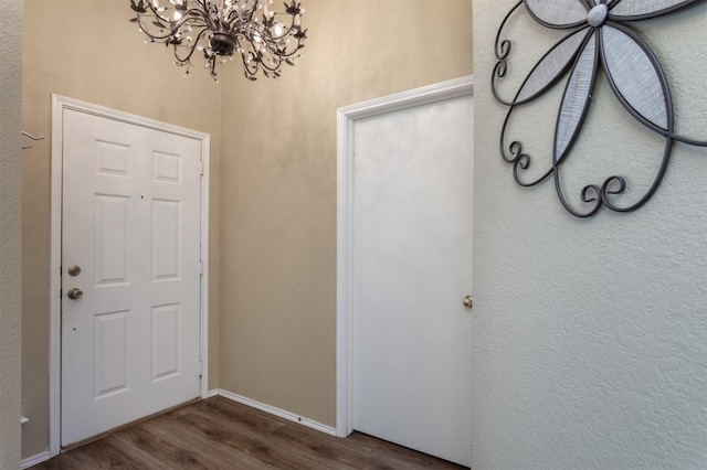 foyer featuring baseboards, an inviting chandelier, and dark wood-style flooring