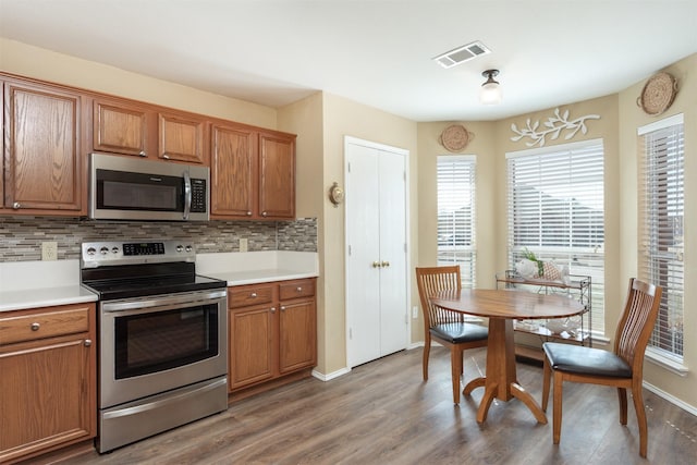 kitchen with decorative backsplash, brown cabinetry, visible vents, and appliances with stainless steel finishes