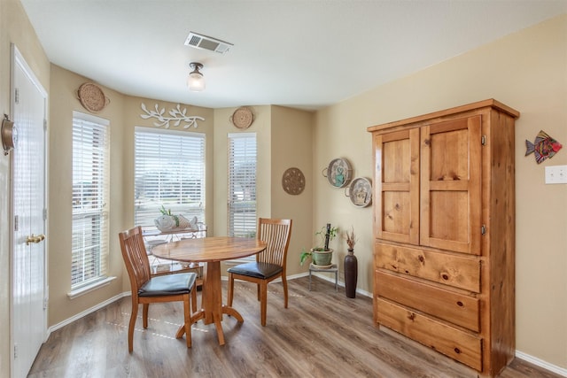 dining area with light wood-type flooring, visible vents, and baseboards