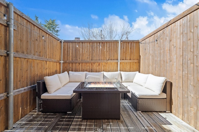 wooden terrace with a fenced backyard and an outdoor living space with a fire pit