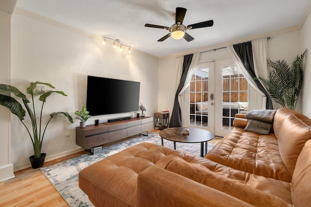 living area with baseboards, a ceiling fan, wood finished floors, crown molding, and french doors