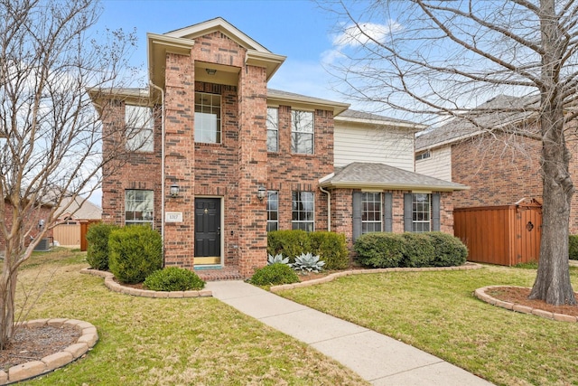 view of front of home featuring a shingled roof, a front yard, brick siding, and fence