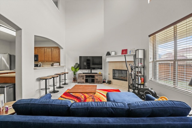 living room featuring a tile fireplace, arched walkways, and a high ceiling