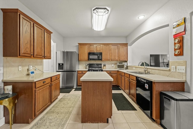 kitchen featuring a center island, a sink, light countertops, black appliances, and backsplash