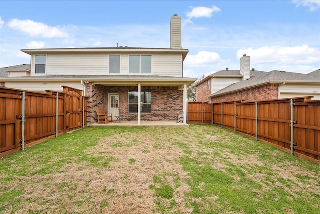 rear view of house with a patio area, a yard, a fenced backyard, and brick siding