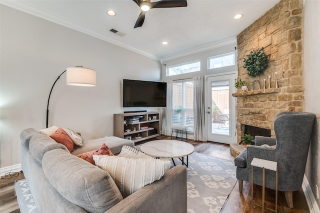 living room with a fireplace, wood finished floors, visible vents, a ceiling fan, and ornamental molding